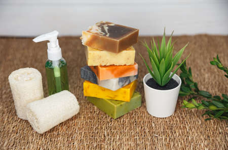 Different personal hygiene objects. Set of bath and spa accessories. Handmade natural soap, facial brush, terry towels, loofah sponge with green plant. Healthy lifestyle concept. Beauty, skin careの写真素材