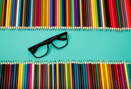 Color pencils and glasses on blue background. Office background. Close up. Back to school. Top view, flatly, layoutの写真素材