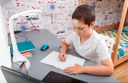 Schoolboy using desktop computer for online study homeschooling during home quarantine. Home...