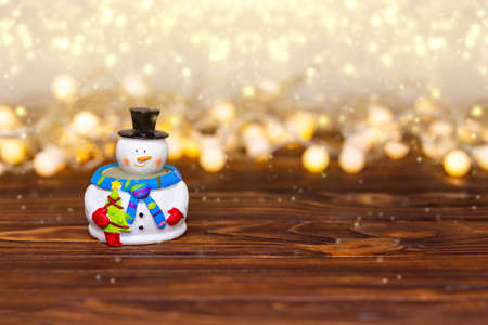 Funny snowman with golden lights on rustic wood with copy space. Merry Christmas, greeting card...