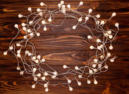 Christmas frame from Christmas lights on dark rustic wooden background. Christmas and New Year...