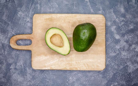 Raw avocado on wooden background. Avocado cut in the middle on a wood cutting board. Ripe avocado...