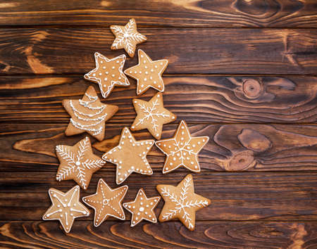 Assorted Christmas gingerbread cookies in the shape of a Christmas tree on wooden table with copy...