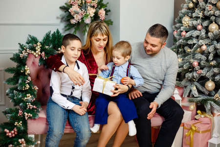 Family in living room opening Christmas presents. Cheerful family is celebrating New Year together....