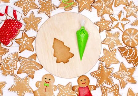 Delicious Christmas gingerbreads with decorations on cutting board. Handcrafted and painted by hand....