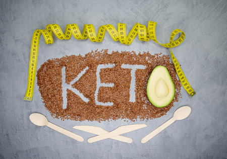 Ketogenic diet and healthy eating. Diet for the healthy body. Keto diet inscription. Word and a half of avocado on gray background. Horizontal image. Healthy products. Low carb dieting. Balanced dietの写真素材