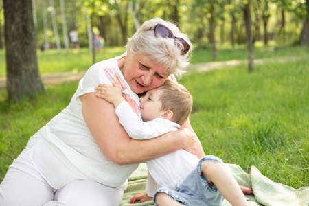 Senior granny cuddle with cute preschooler grandchild. Happy grandma with grandson embracing. Grandmother hugging boy. Family generation communication. Woman with kid spending time together outdoors.の写真素材