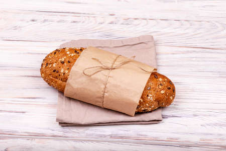 Loaf of fresh bread on white background. Ecological food. Freshly baked organic sourdough bread into sustainable paper bag in bakery. One loaf of freshly baked buckwheat bread in a paper bag isolated.の写真素材