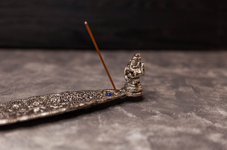 Procedure aromatherapy. The concept of zen and meditation. Incense stick burning on a metal stand. Indian incense sticks smoke in a stand on gray background. Traditional oriental aromatherapy.の写真素材