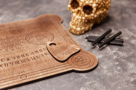 Mediumship divination equipment. Ouija board on grey background.Fortune teller and black magic concept. Spirituality, occultism. People conducting a seance using a talking spirit board.の写真素材
