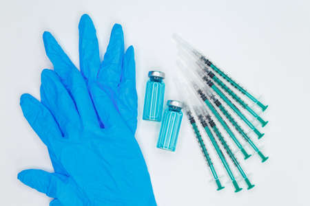 Diabetes insulin injection syringe. Disposable syringe and injection vial. Medical syringe and ampoule on blue background. Human hand holding vial with vaccine against corona virus. Vaccinationの写真素材