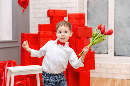 Funny kid congratulate mother on holiday and give flowers. Cute child congratulating mother Happy...