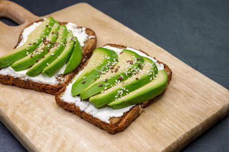Sandwich with avocado and cottage cheese. Sliced avocado on toasted bread for healthy breakfast or...