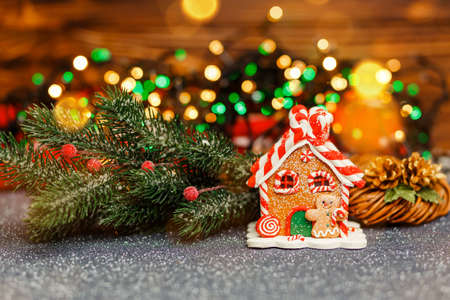 Morning in the bright living room. Holiday mood. Homemade gingerbread house in living room. Defocused lights of Christmas tree. Gingerbread house over defocused lights of Chrismtas decorated fir treeの写真素材