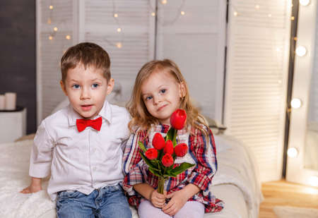 Cheerful young couple hugging. Sweet little girl and cute boy have a date. Young couple hugging. Romantic kiss. Beautiful young couple with tulips. Boy and girl give a gift on Valentine day.の写真素材