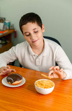 Diet or healthy lifestyle concept. Happy boy eating a french fries. Painful preteen boy having...