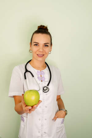 Doctor nutritionist writing case history, dietitian prescribing recipe. Portrait of young woman nutritionist in medical gown. Smiling nutritionist in her office. Healthcare and diet. Weight lossの写真素材