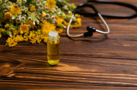 Healing herbs on wooden table. Herbal oil in a glass bottle. Cosmetic organic essential oil. Herbal medicine bottle with flowers. Fresh herbs from the garden for aromatherapy.の写真素材