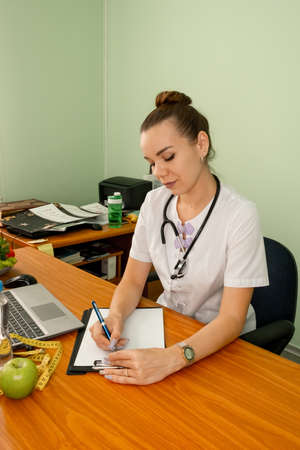 Dietician working on diet plan with digital tablet. Female nutritionist working at her desk. Right...