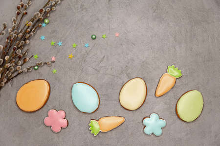 Delicious glazed cookies in blue, yellow , orange and pink colour on grey. Willow branches on grey....