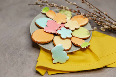 Homemade easter cookies in the shape of a funny rabbit, eggs, carrots, flowers on plate. Beautiful...