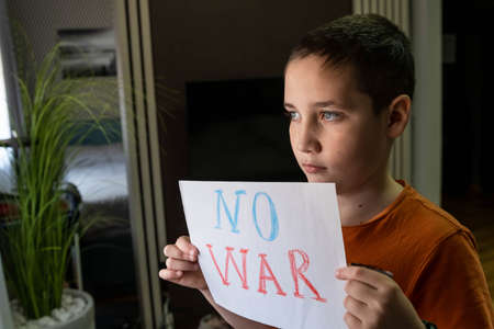 Slogan of peace without war. Child with message Stop War. A child against War. Antiwar, family, patriotism, unity, support, crisis. Crying boy asks to stop the war. The child holds a posterの写真素材