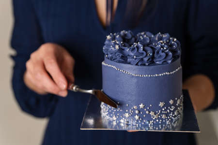 Birthday cake held by a baker in a bakery. Portrait of caucasian woman sharing fresh cake. Chef...