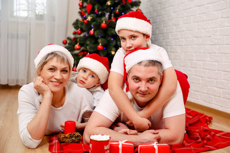 Happy family lying on the floor at home. Portrait of happy family with Christmas gifts. Children...