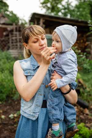 Mother carrying her toddler baby and eat fruit together. Mom and her son having snack time together. Mother giving son strawberries to taste. Beautiful mother feeding her boy. Mom feeding little baby.の写真素材