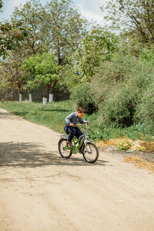 Happy child riding his bike outside his home. Young boy learning to ride his bicycle. Portrait little boy enjoy having fun riding exercise bike. Child first bike. Kid outdoors sport summer activitiesの写真素材