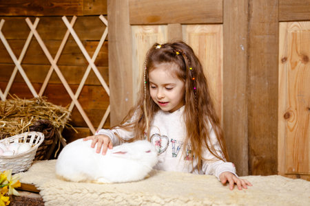 Little girl caring and feeding her loving pet food. Farming and gardening for small children. Cheerful girl looking at rabbit. Cute girl with real bunny. Children education and pet love concept.の写真素材