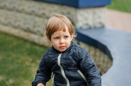 Portrait of a serious young boy. A young boy cheering. Child smiling and looking at camera. Portrait of adorable brunette child. Little shocked baby. Child boy outdoors on a warm sunny summer day.の写真素材