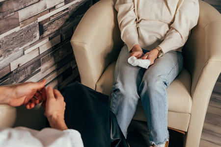 Psychologist counseling patient. Hands of man attending private psychologal therapy, doctor making notes while patient sharing his thoughts. Young female doctor in consultation with patientの写真素材