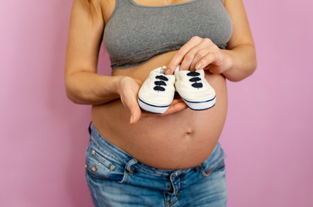 Anticipation and preparation: a close-up image of a joyful expectant mother holding tiny baby...