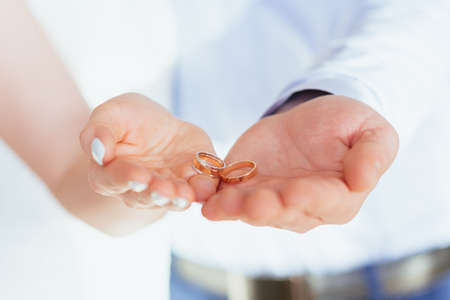 Two gold wedding rings lie on the palms of the bride and groom. Just married couple. Soft focusの写真素材