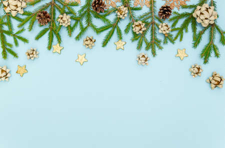 Green Christmas tree branches with New year's toys. Cones, bows and Gold stars on a sky-blue...