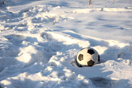 A soccer ball is lying on the white snow. Ball on a snow-covered field after the gameの写真素材