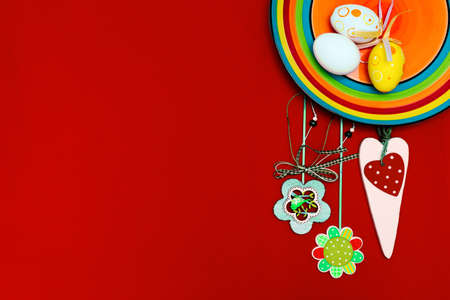 Easter composition with eggs, flowers, carrots and a rainbow on a red background. Orange plate. Red background. Place for text. Happy Easter. Easterの写真素材