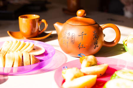 Chinese ceramic teapot. The kettle is on the breakfast table. A table in bright sunlightの写真素材