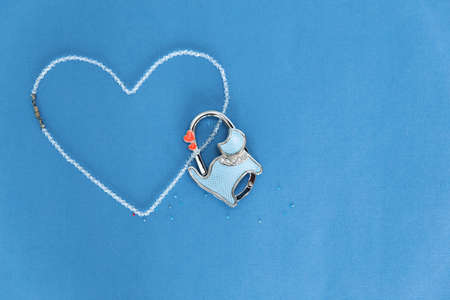 Beads of rock crystal laid out in the shape of a heart on a blue background. Nearby is a lockable lock in the form of a cat. Love concept, wedding Valentine's day. Place for text.の写真素材