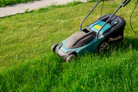 Electric lawn mower Makita. The green lawn is mowed with a lawn mower. The concept of a beautiful manicured lawn and garden. Abakan, Russia-June 12, 2020のeditorial素材