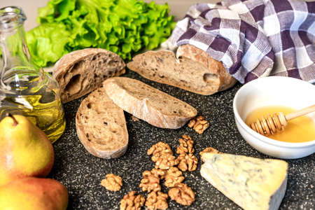 sliced ciabatta, pear, Dor blue cheese, walnuts, honey, olive oil and green salad leaves on the...