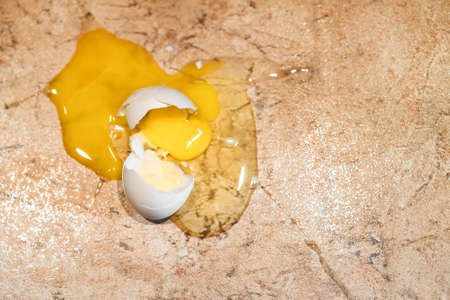 The egg is broken on a stone marble floor. Front focus