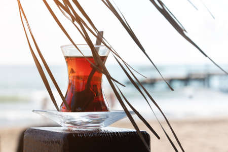 summer, a glass of tea, on the beach, against the background of the sea. The concept of summer holidays and vacationの写真素材