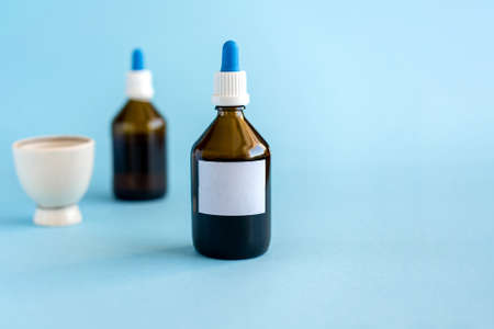 Homeopathic drops and two glass bottles on a blue background. Herbal medicine alternative homeopathy, healthcare concept and pills. copyspace for textの写真素材
