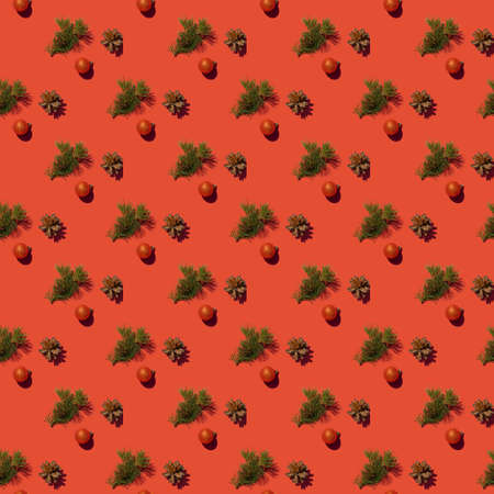 Seamless creative pattern with a spruce branch, a cone and a Christmas toy on a red background. The concept of printing on fabric, wrapping paper.の写真素材