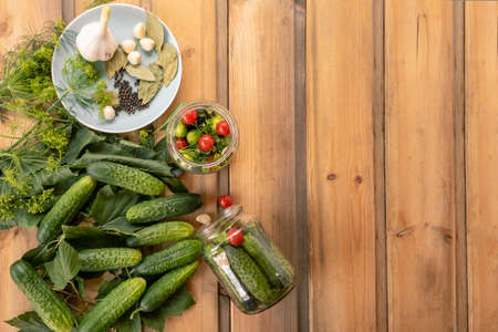 Fresh cucumbers ready for canning and pickling with dill, garlic and spices on a wooden table and in glass jars. Copy spaseの写真素材