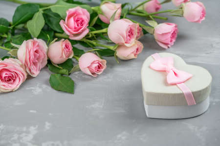 Gift box and a beautiful bouquet of pink roses on a gray backgroundの写真素材