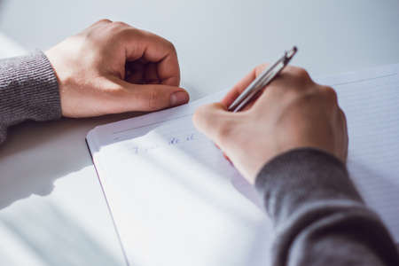 An image of a man's hand writing the phrase I can do it! In a Notepad with a ballpoint pen. The man...