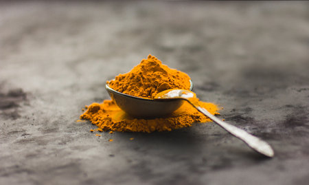 Spices turmeric in a spoon on a dark background, seasonings and healthy foodの写真素材